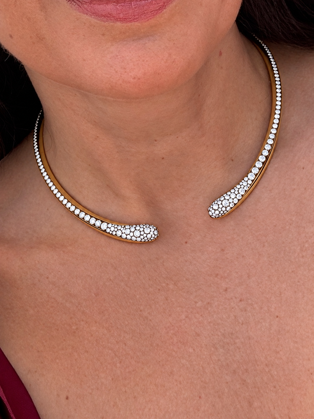 Model wearing a yellow gold open torque necklace set with pavé diamonds along both ends