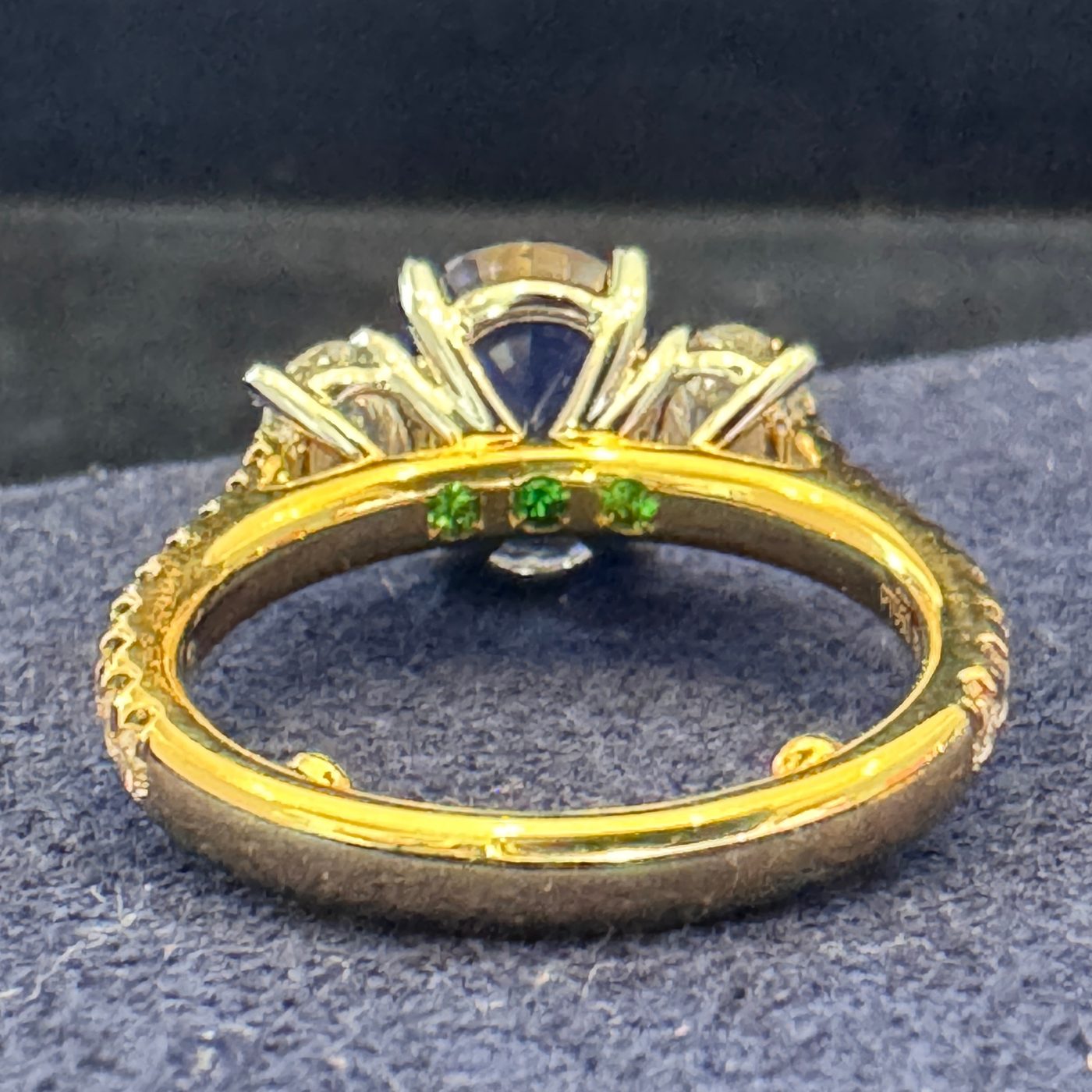 The sapphire ring seen from behind, showing the hidden emeralds inside the band